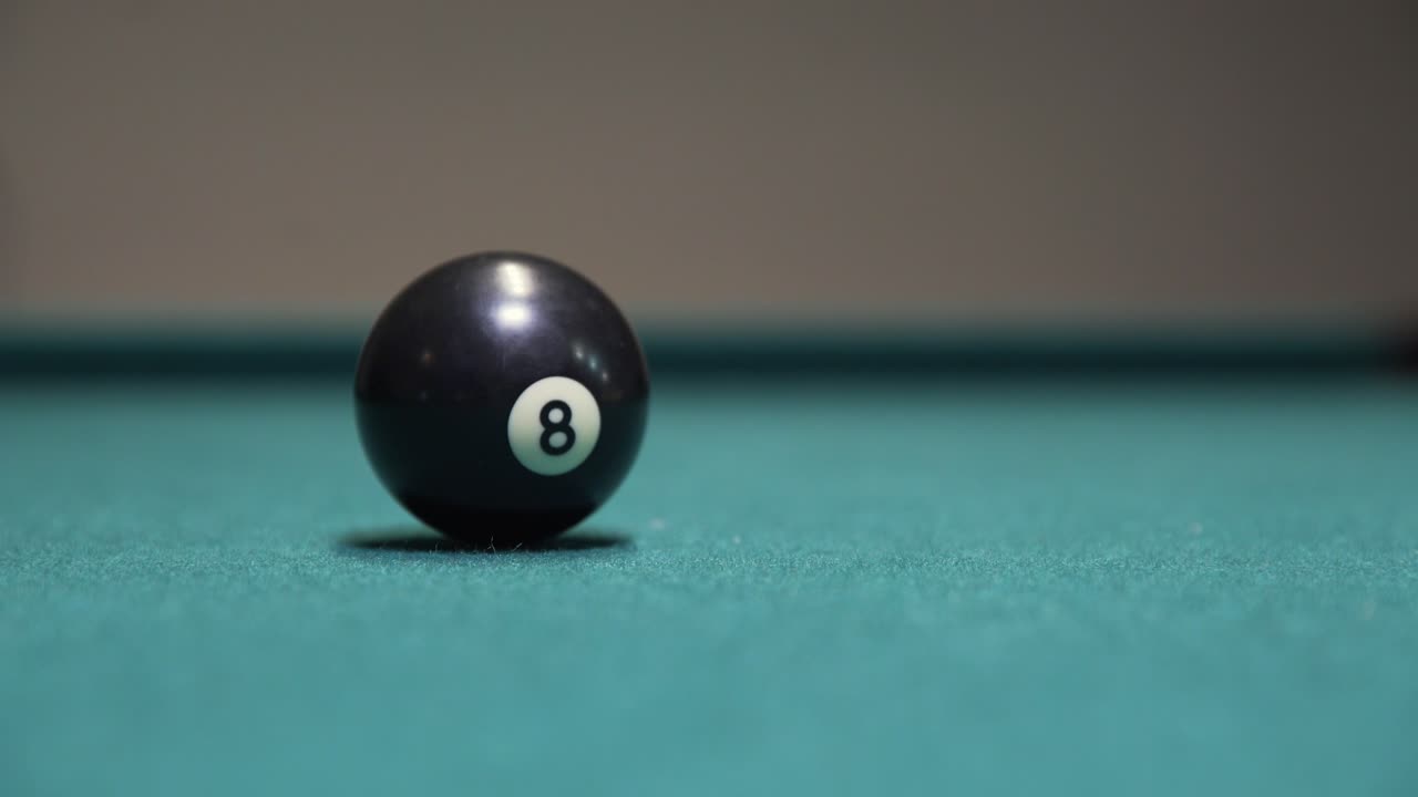 Black 8-ball spinning to a stop on a billiards table