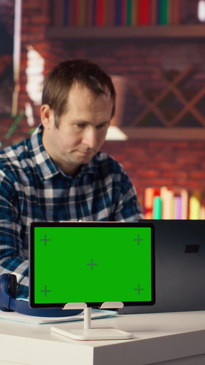Vertical video Mockup tablet next to worker listening music, analyzing data on laptop