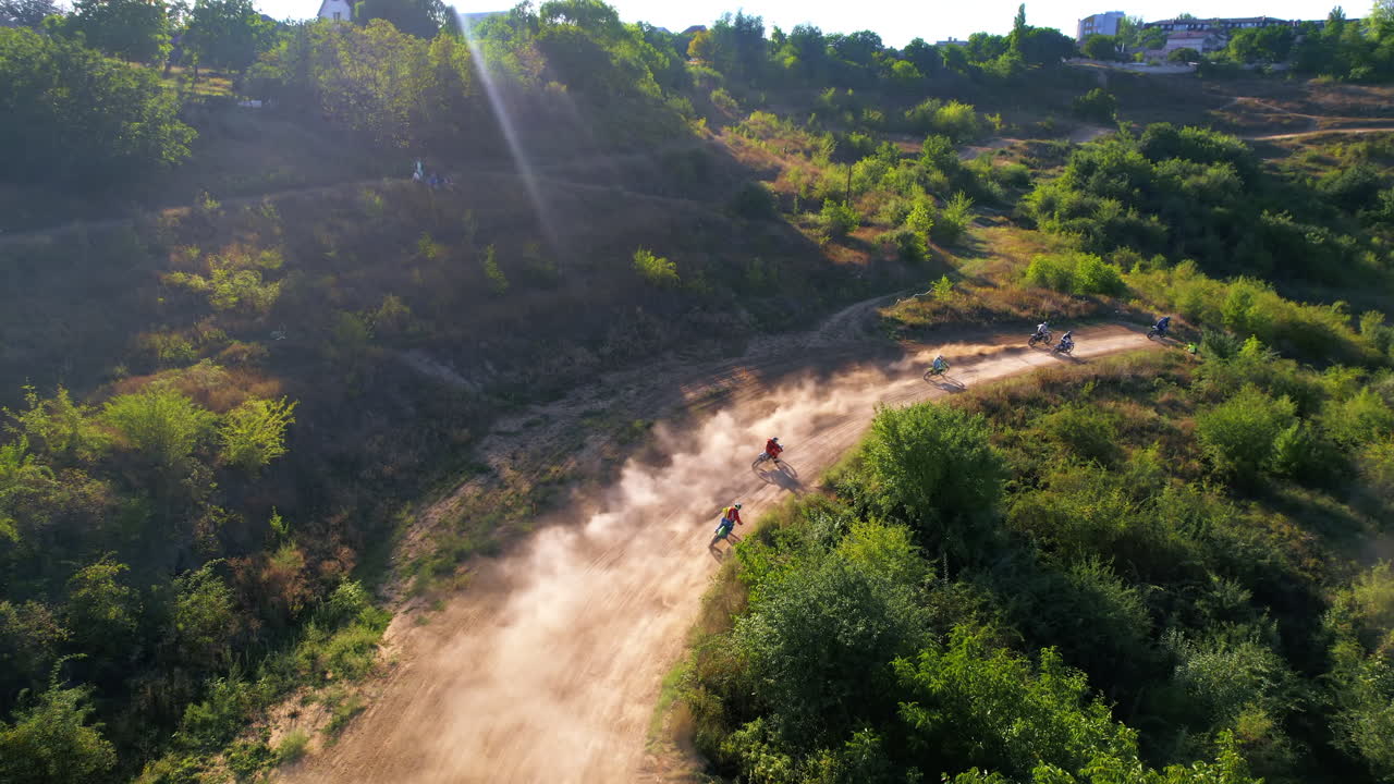 Vista aerea da drone di motociclisti che saltano da trampolini durante una gara di motocross, pista fangosa, rally di moto, vegetazione circostante