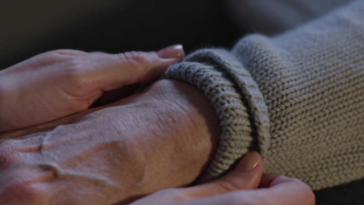 Noticing cuff, adjusting caregiver rolling knit sweater cuff at home, smoothing wrist for comfort