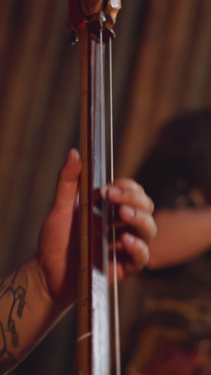 Musician plays string instrument with long thin neck groupmate taps drums in traditional cabin closeup. Festival of mystical Altai music. Folk band