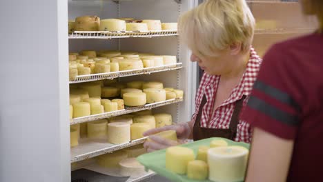 trabajadora poniendo cabezas de queso cocidas en un enorme refrigerador industrial en una fábrica de queso