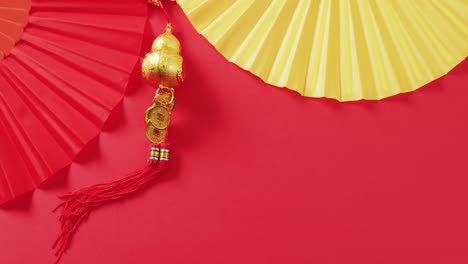 Video-of-close-up-of-chinese-fans-and-decorations-on-red-background