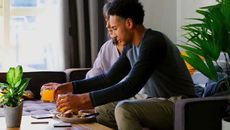 side view of mixed-race young woman using mobile phone on sofa in a comfortable home 4k