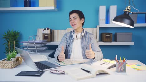 Male-student-studying-on-laptop-smiling-making-positive-gestures-with-both-hands.