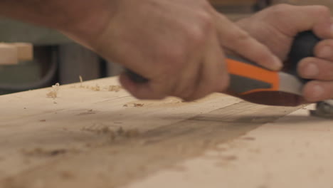 low angle slow motion close up of a carpenter using a planer on wood boards in his shop