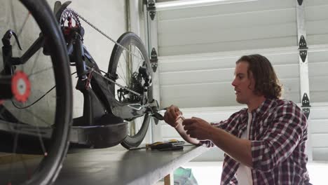 Fokussierter-Kaukasischer-Mann,-Der-Fahrrad-Mit-Werkzeugen-In-Der-Garage-Repariert