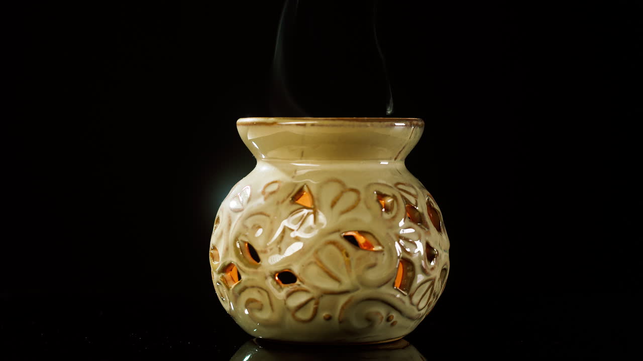 Diffuseur d’aromathérapie en céramique avec des volutes de fumée sur fond noir