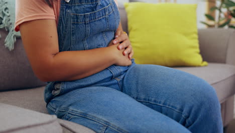 woman, hands and stomach ache on living room sofa