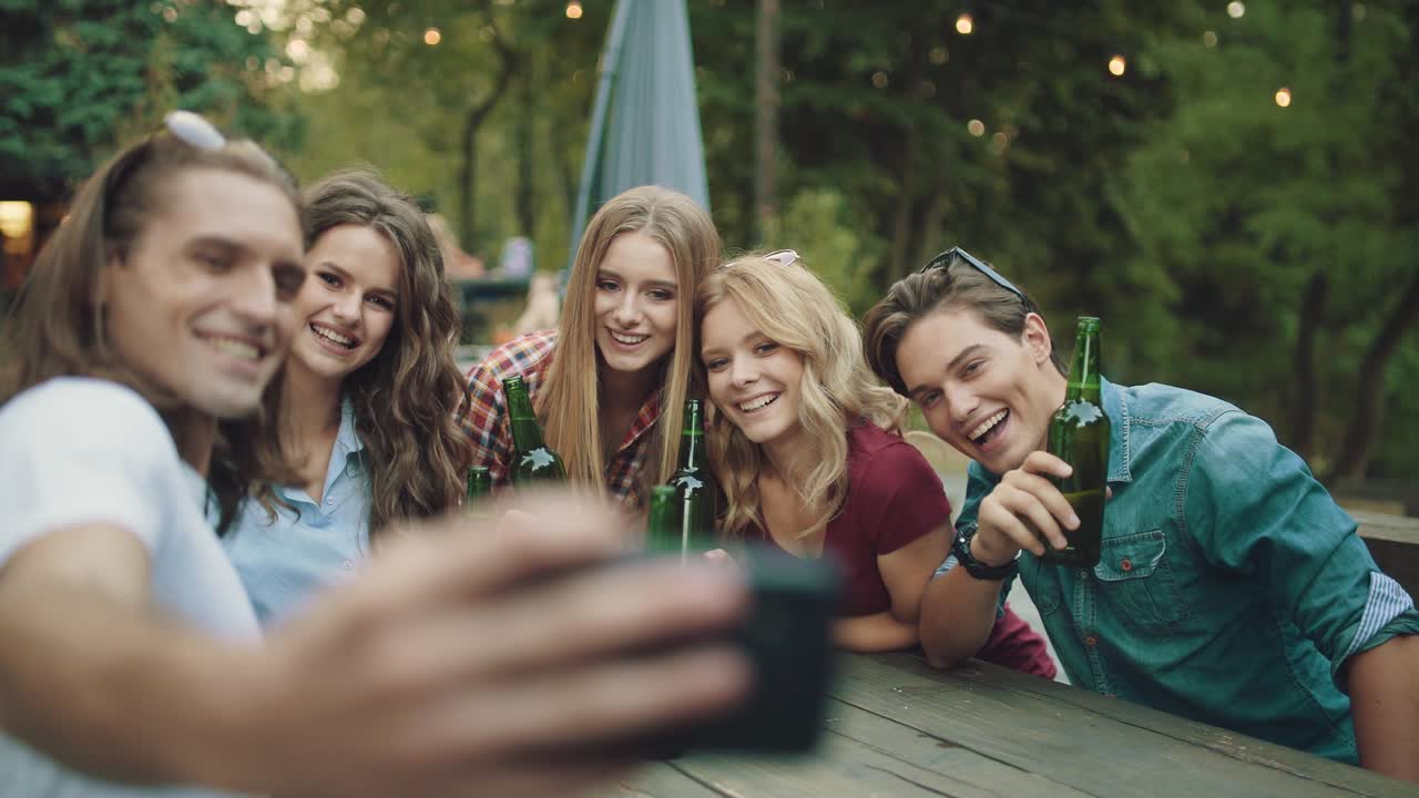 grupo de amigos bebiendo cerveza y tomando fotos en el teléfono