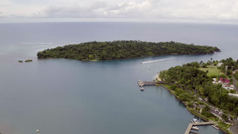 aerial view of navy island in port antonio in jamaica whilst a speedboat sails through the channel between the harbour and island