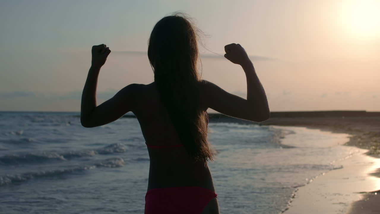 una mujer concentrada entrenando en una playa de arena, una chica bonita haciendo ejercicios en la costa.