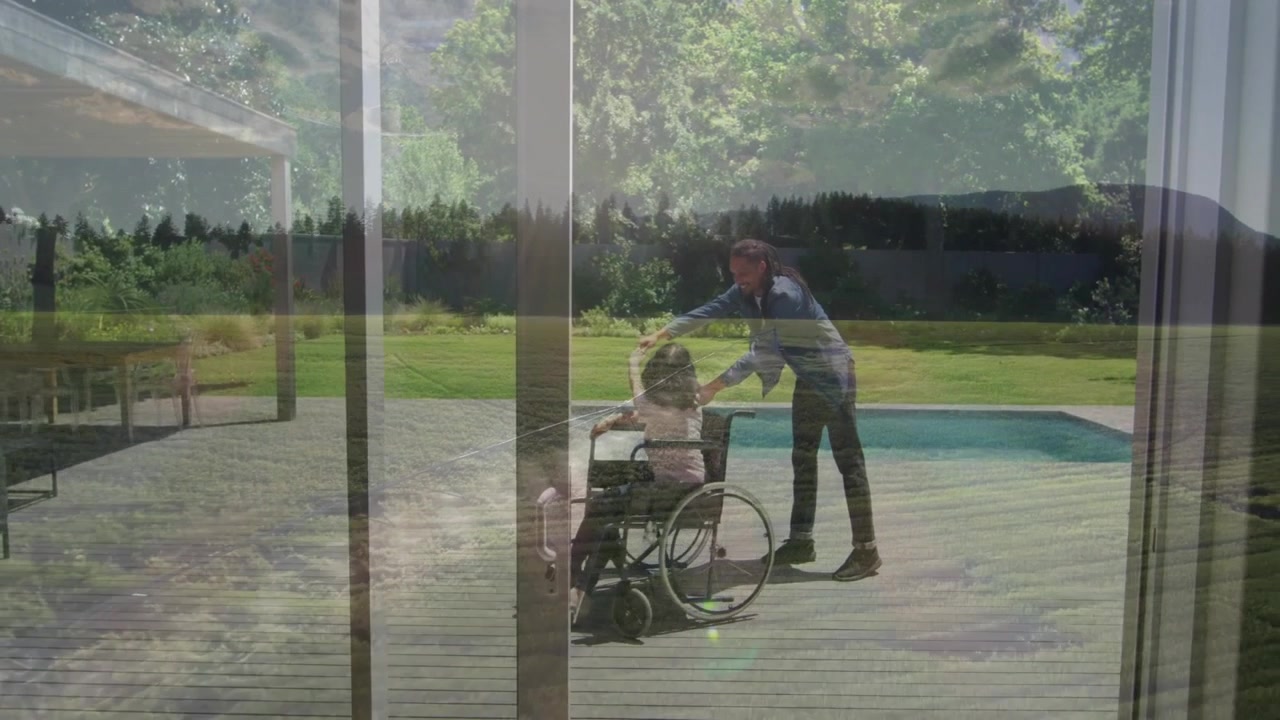 Pushing wheelchair on wooden deck, person enjoying lush green landscape view