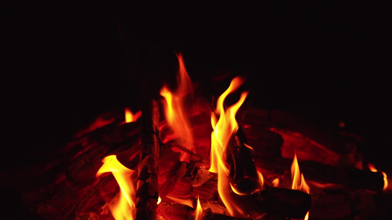Mesmerizing view of wood burning out in bonfire. Red smoldering embers sparkling in the campfire. Close up.