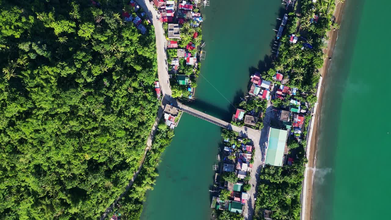 Scenic aerial top-down flyover of coastal barangay town connected to lush, hillside village via river bridge - Batalay, Catanduanes, Philippines