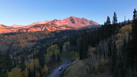 mountain lit peaks and an airstream rolling down a dirt road on an epic early morning in colorado