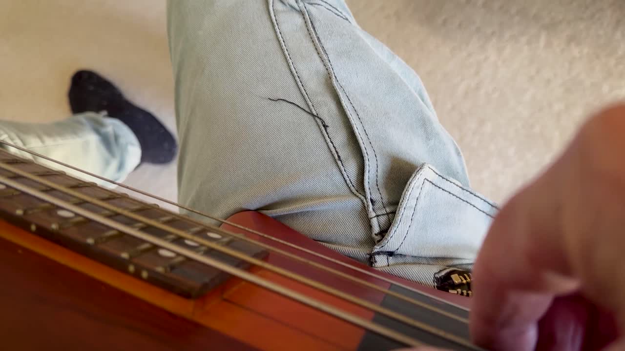pov de un hombre caucásico maduro tocando el bajo, arrancando y tocando con los pies