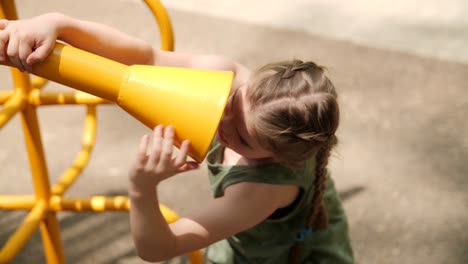 Junges-Mädchen,-Das-Auf-Einem-Kinderspielplatz-In-Eine-Röhre-Spricht