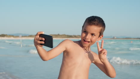 cheerful boy looking to camera at seashore. smiling guy taking selfie at beach.