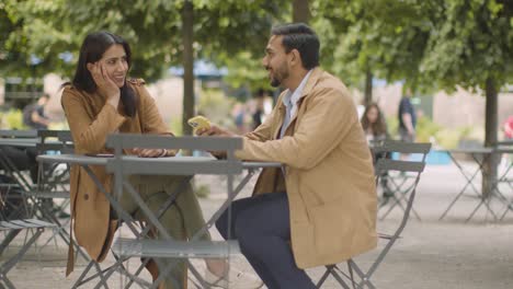 muslim couple on date sitting at outdoor table on city street talking together 2