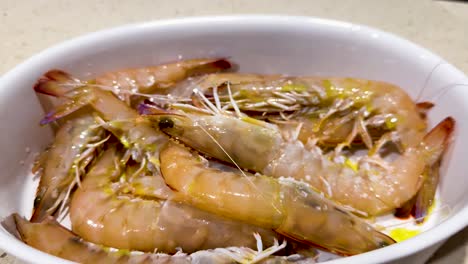 hand sprinkling salt over fresh prawns