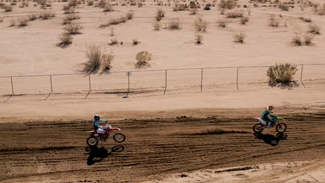 flying over motocross dirt bikes racing in slow motion in mojave desert, aerial