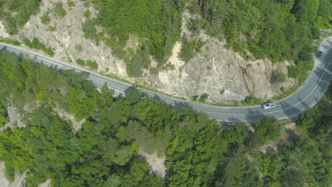 drone chasing silver car on rocky mountain passage road in bulgaria