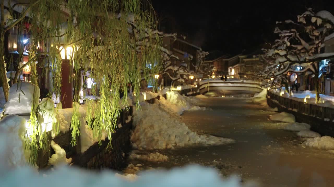 雪に覆われた城崎温泉の夜、昔ながらの旅館と温泉街。