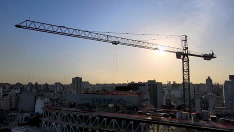 Big-construction-crane-silhouette-against-bright-sunset-sky-at-development-site