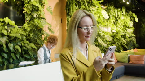 mujer rubia usando un teléfono inteligente en un hotel