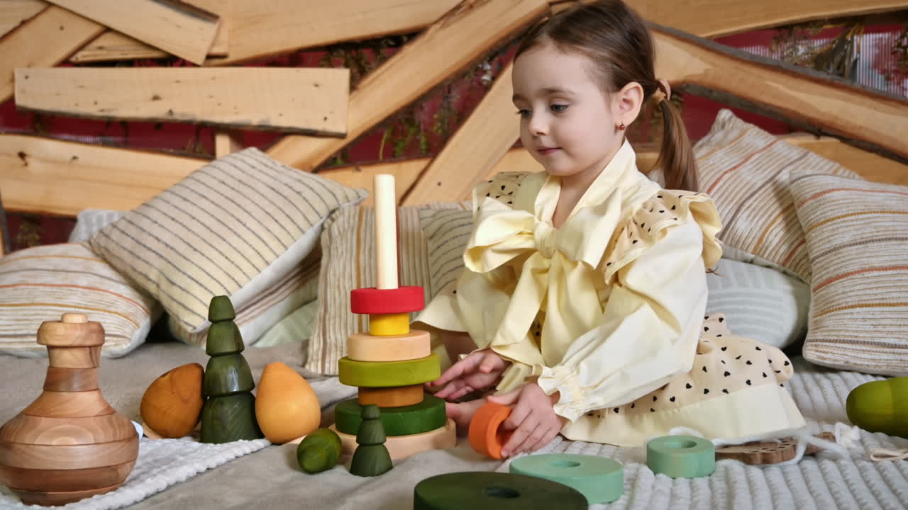 Little girl playing with vibrantly colored blocks of a large wooden pyramid. Ecological and sustainability concept