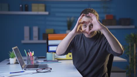un joven empresario pacífico y animado haciendo el corazón a la cámara.
