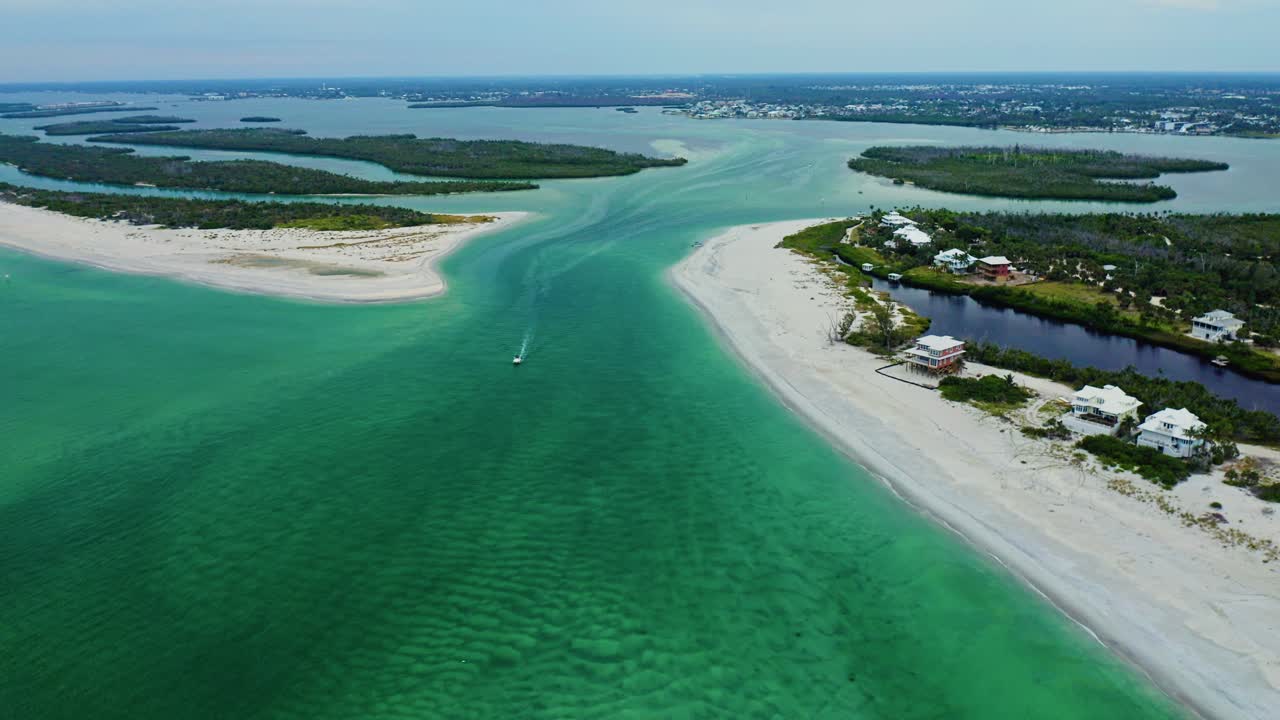 A boat travels through Stump Pass between sweeping sandbar beaches on Manasota Key along Florida’s Gulf Coast, bordered by turquoise shallows and distant mangrove islands