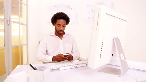 Businessman-texting-on-the-phone-at-his-desk