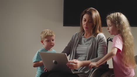 preescolares curiosos y niños pequeños molestan a la madre trabajando en la computadora portátil