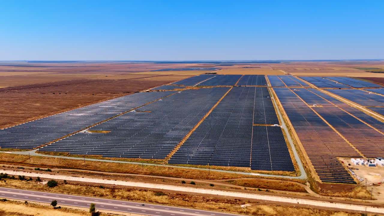 Flight along the road going near the fields in the countryside. Numerous solar panels cover the rural area