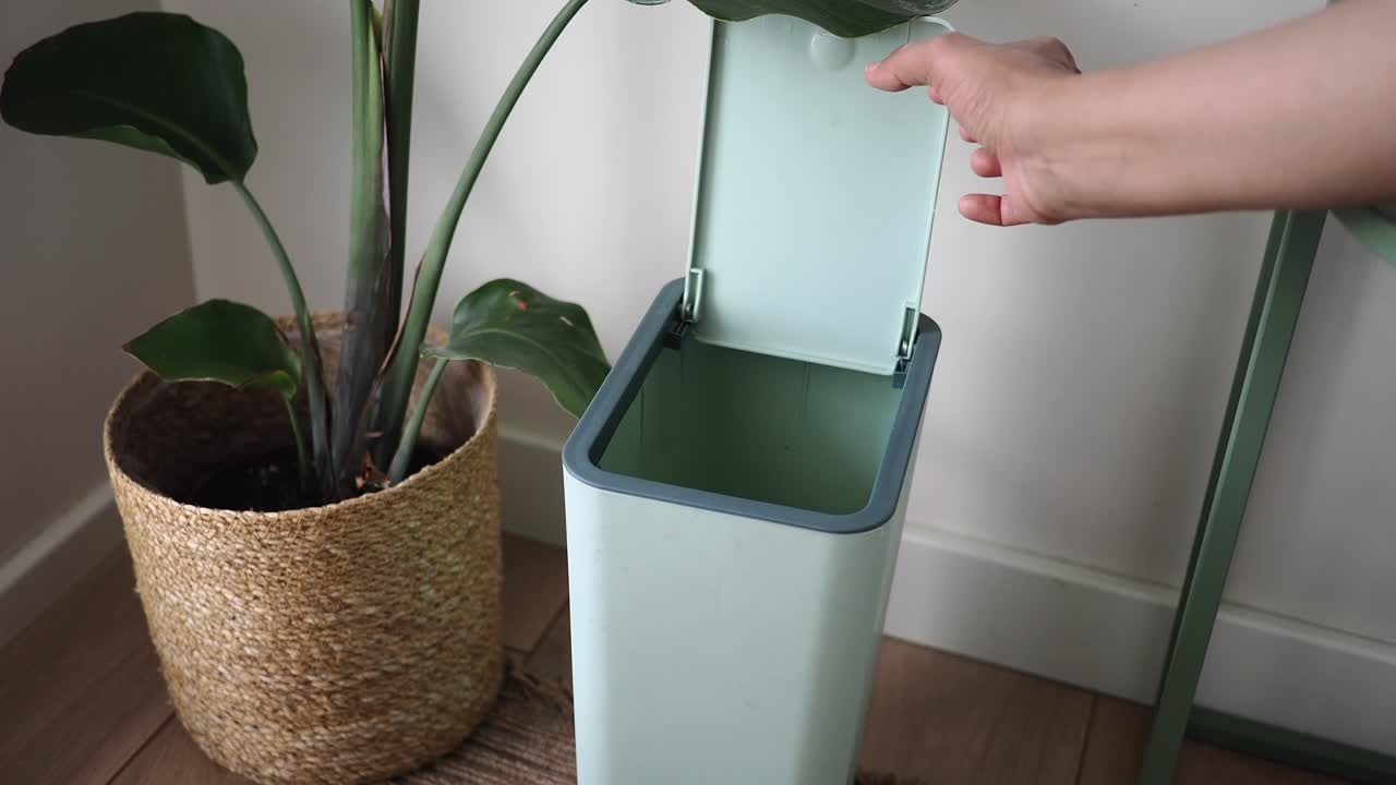 Hand Disposing of Banana Peels into a Compost Bin