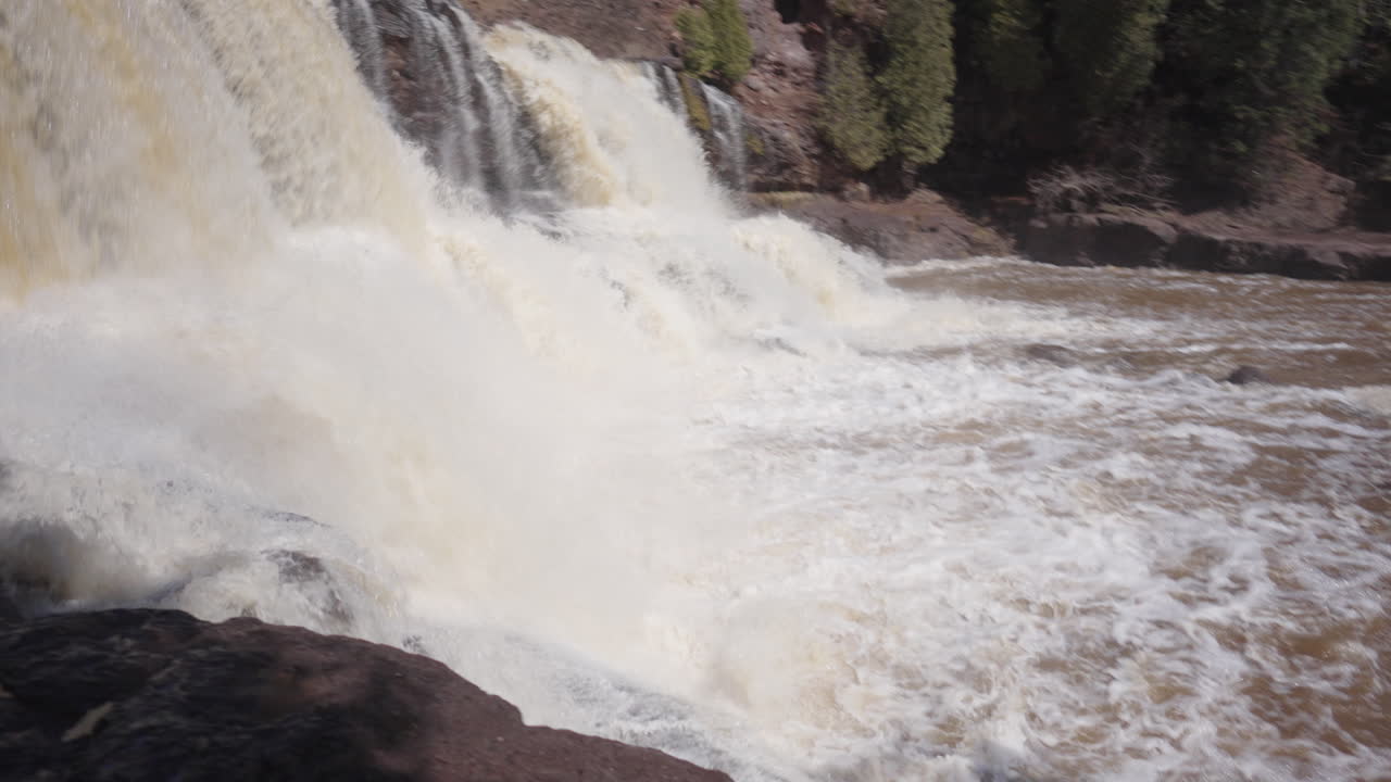 Forceful River Waterfall Rushing Down Forested Cliffside