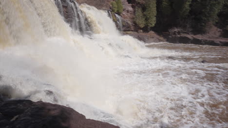 Forceful-River-Waterfall-Rushing-Down-Forested-Cliffside