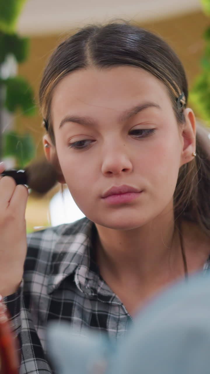 Teen girl adjusting vanity mirror, Youthful girl setting up mirror in retail environment, Teen girl arranging her makeup station with studio lights and mirror in shopping mall setting
