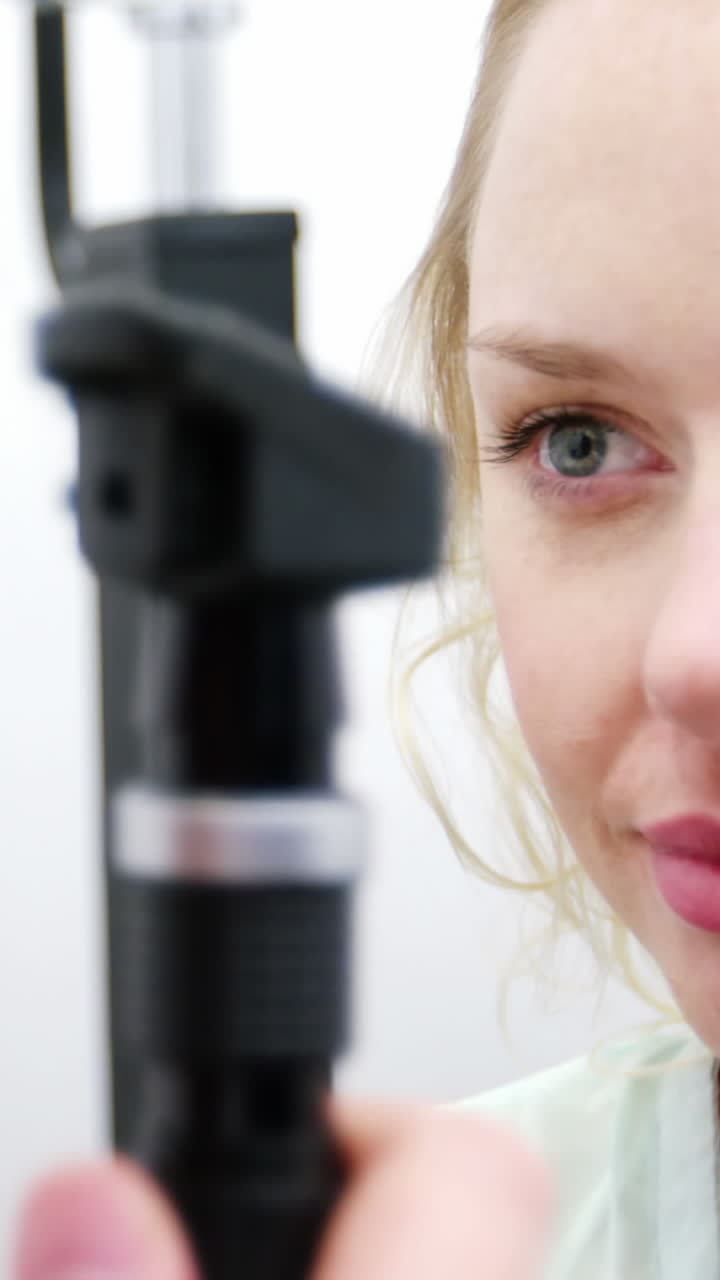 Optometrist examining female patient through ophthalmoscope