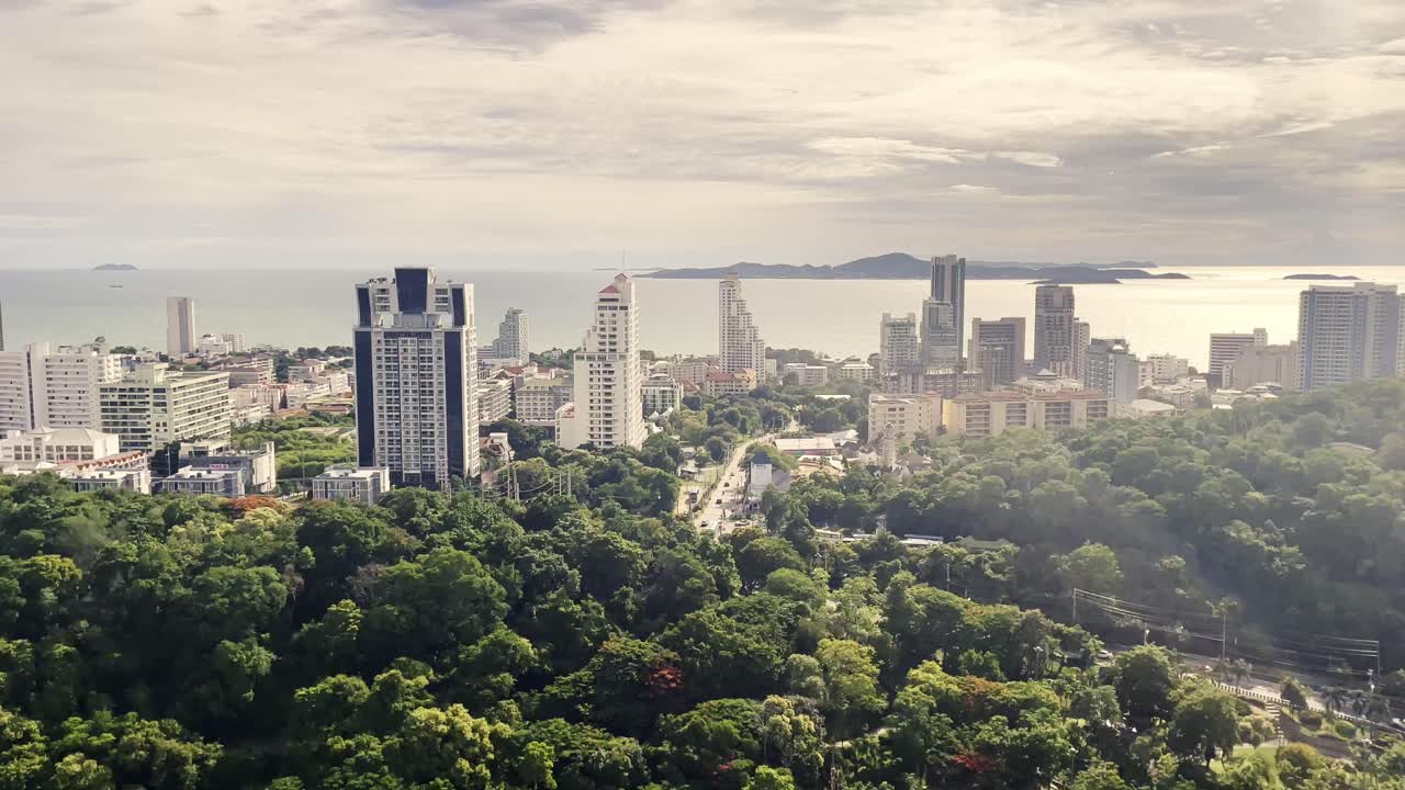 Vista panoramica di una città costiera con alberi verdi lussureggianti ed edifici a più piani che si affacciano sull'oceano.