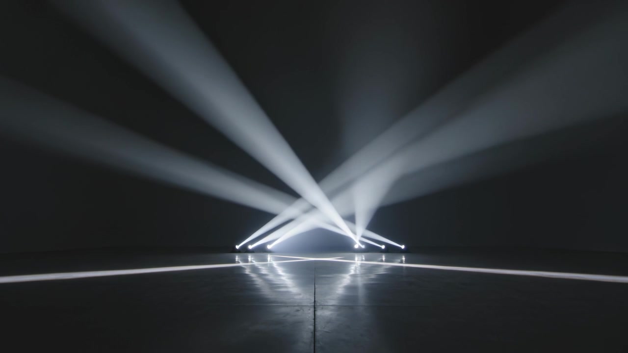 Drejer på signal, moving heads projicerer stråler hen over scenegulvet med røg, hvilket skaber et lysmønster.