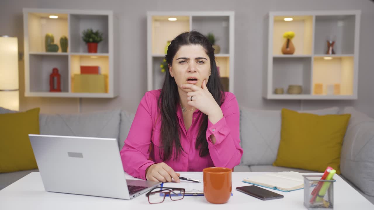 mujer trabajadora de oficina en casa mirando a la cámara con curiosidad y confusión.