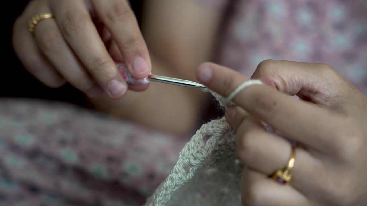 Close up of hands skillfully creating intricate patterns with yarn and a crochet hook, showcasing the art of crochet
