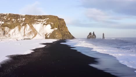 drones 4k, tomas cinematográficas aéreas del dramático paisaje del acantilado de gerouberg, y el mar nórdico, con las olas estrellándose hacia la costa tratando de llegar hacia el paisaje de nieve blanca