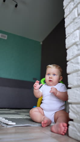 adorable chubby caucasian baby sits on the floor. cute child tries to dance sitting. vertical video.