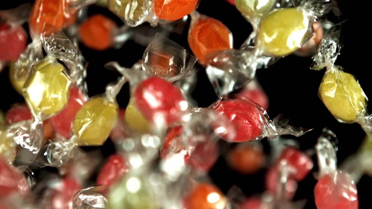 Caramelle incartate e colorate che cadono in super rallentatore.