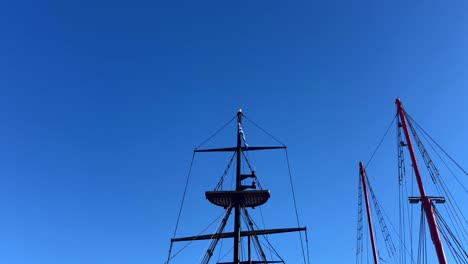 tall sailboat masts with rigging and a greek flag against a clear blue sky at crete island, greece