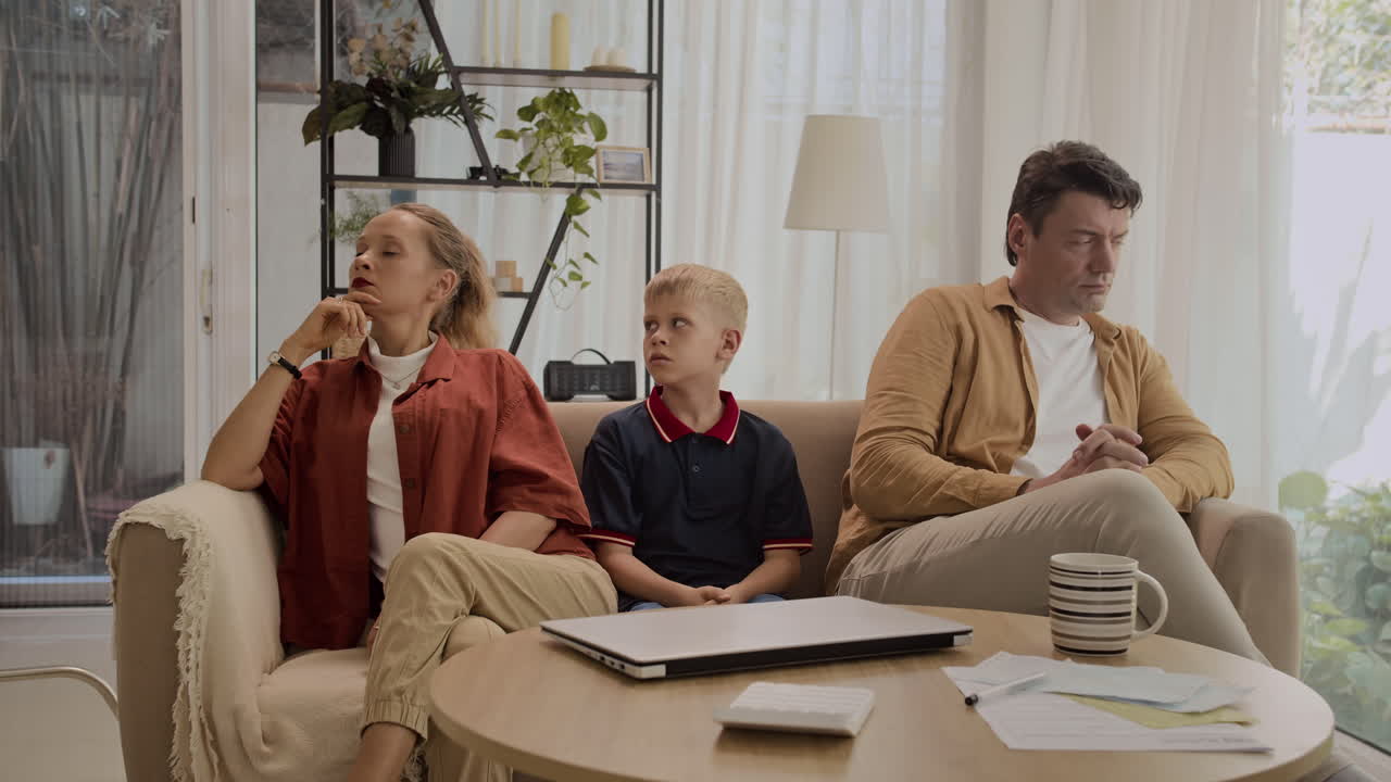 Teenage Son Sitting between Parents Having Argue at Home